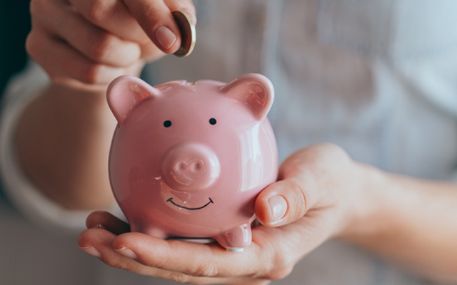 Photo of person putting money in a piggy bank