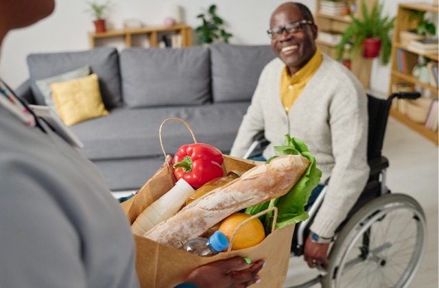 Photo of senior in wheelchair receiving groceries