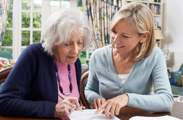 Photo of a woman helping a senior with documents