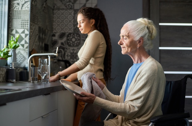Photo of woman helping senior clean dishes