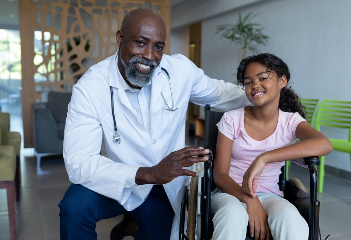 Doctor and patient in wheelchair looking at camera