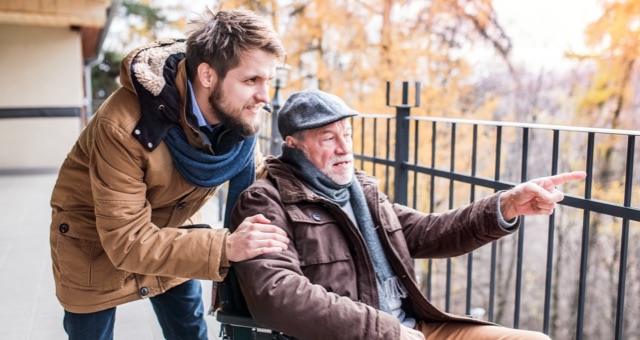 Photo of son pushing senior father in wheelchair