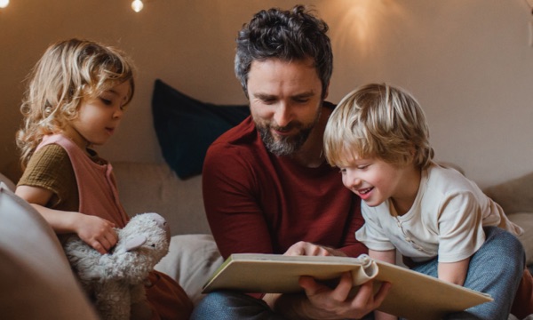 Photo of father reading a book to his children