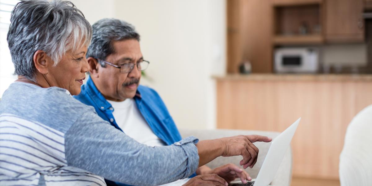 Man and woman on the couch looking at stuff on the computer