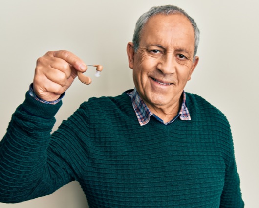 Senior man holding a hearing aid