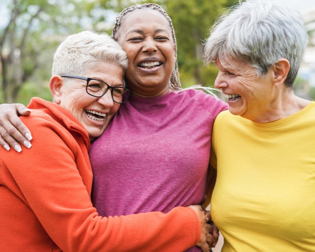 Three senior women smiling and hugging